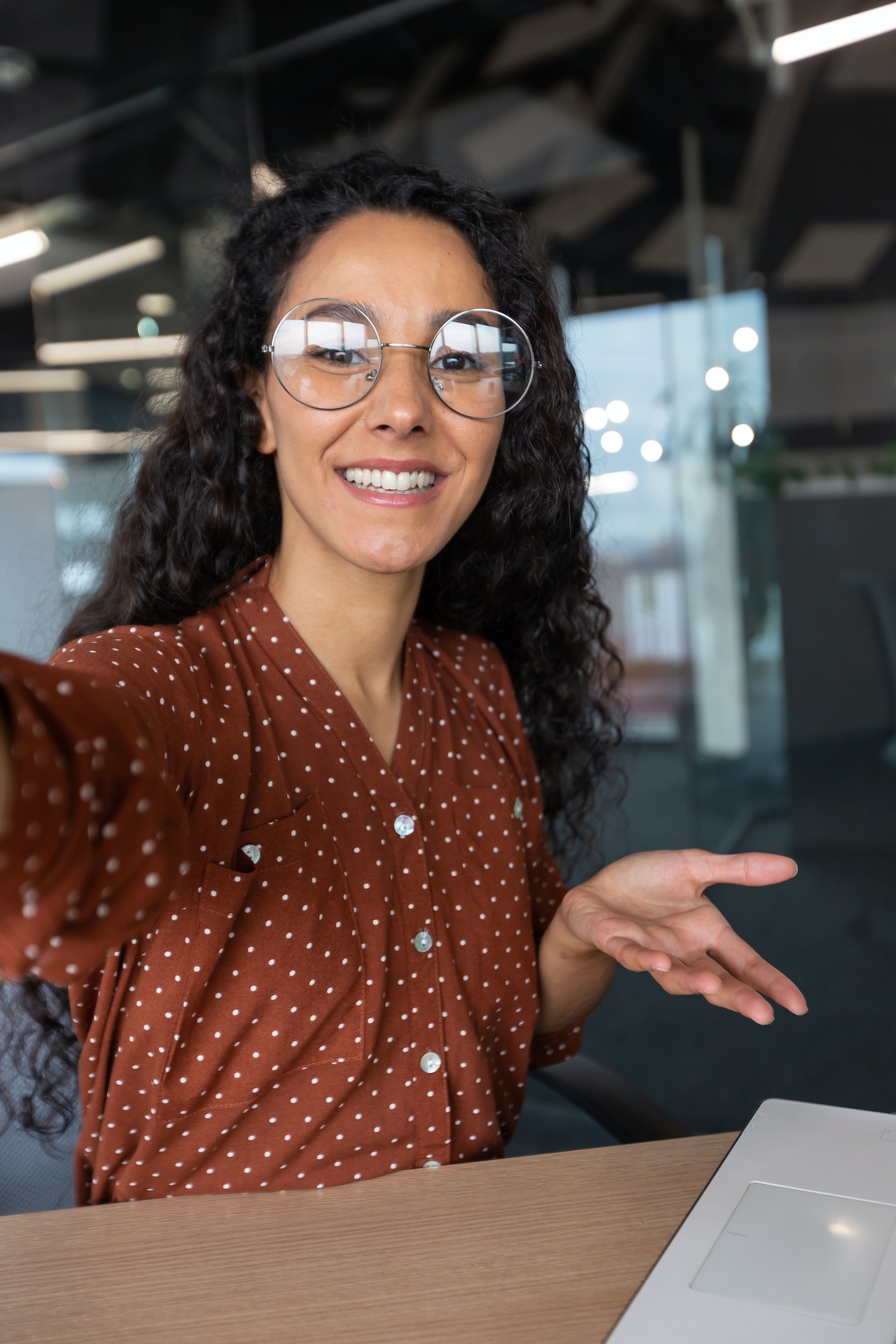 Vertical shot, video call from office hispanic business woman working inside modern office building